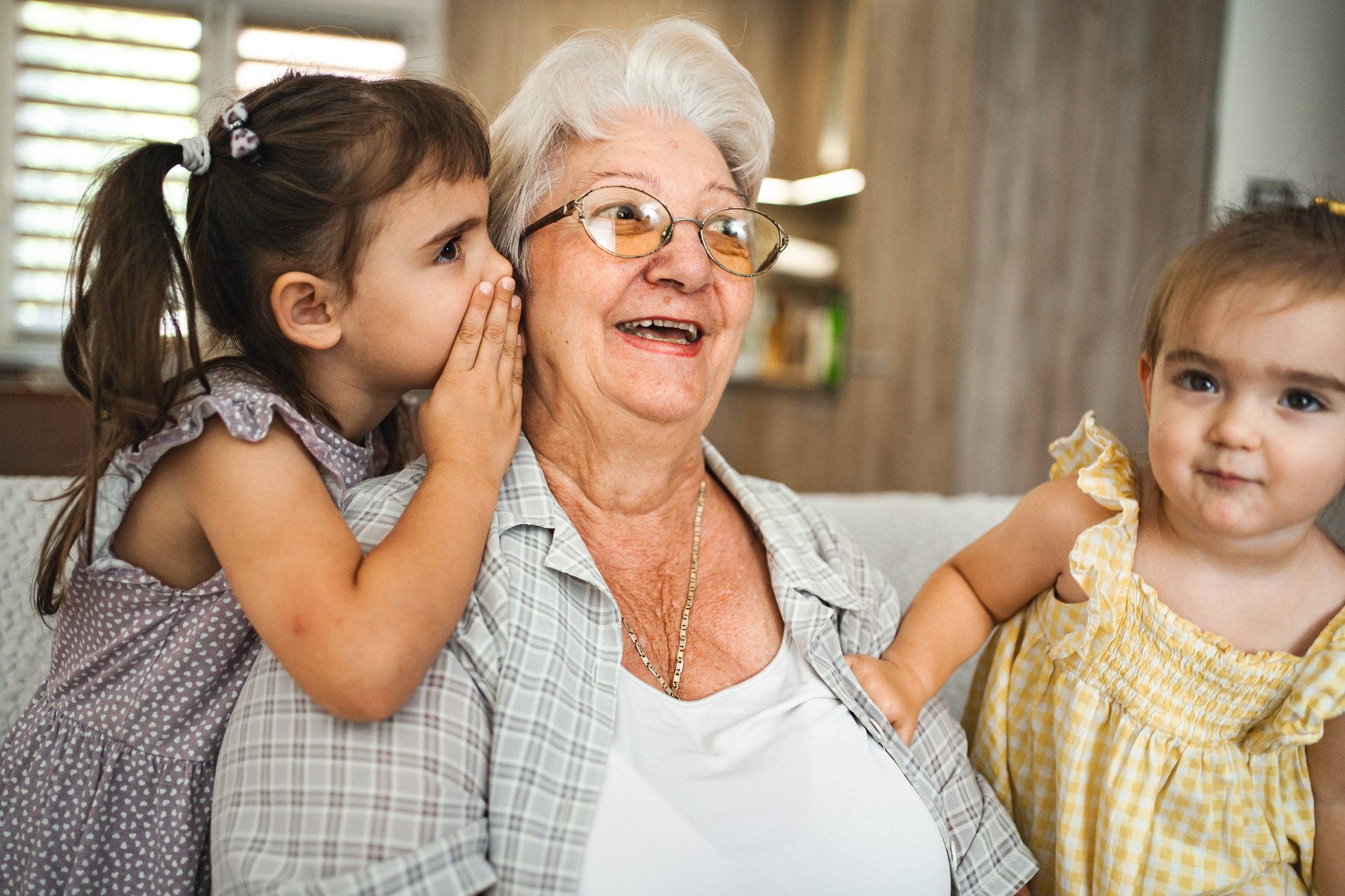 Little girl whispering something to her grandmother at home