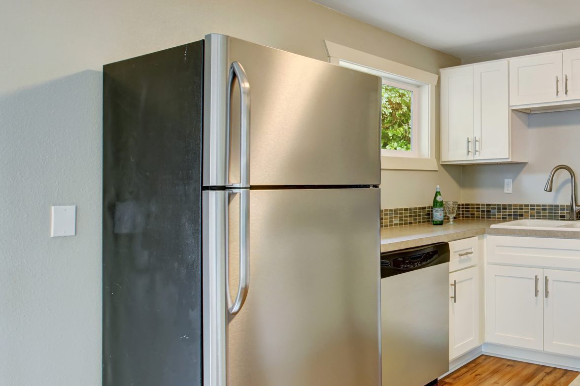 Furnished kitchen room with white cabinets and steel appliances