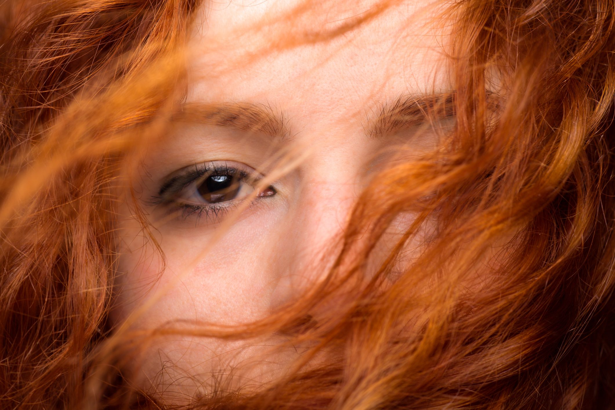 Redhead Woman's Eye Close Up with Blurred Hair