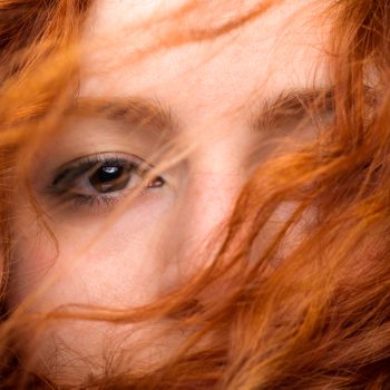 Redhead Woman's Eye Close Up with Blurred Hair