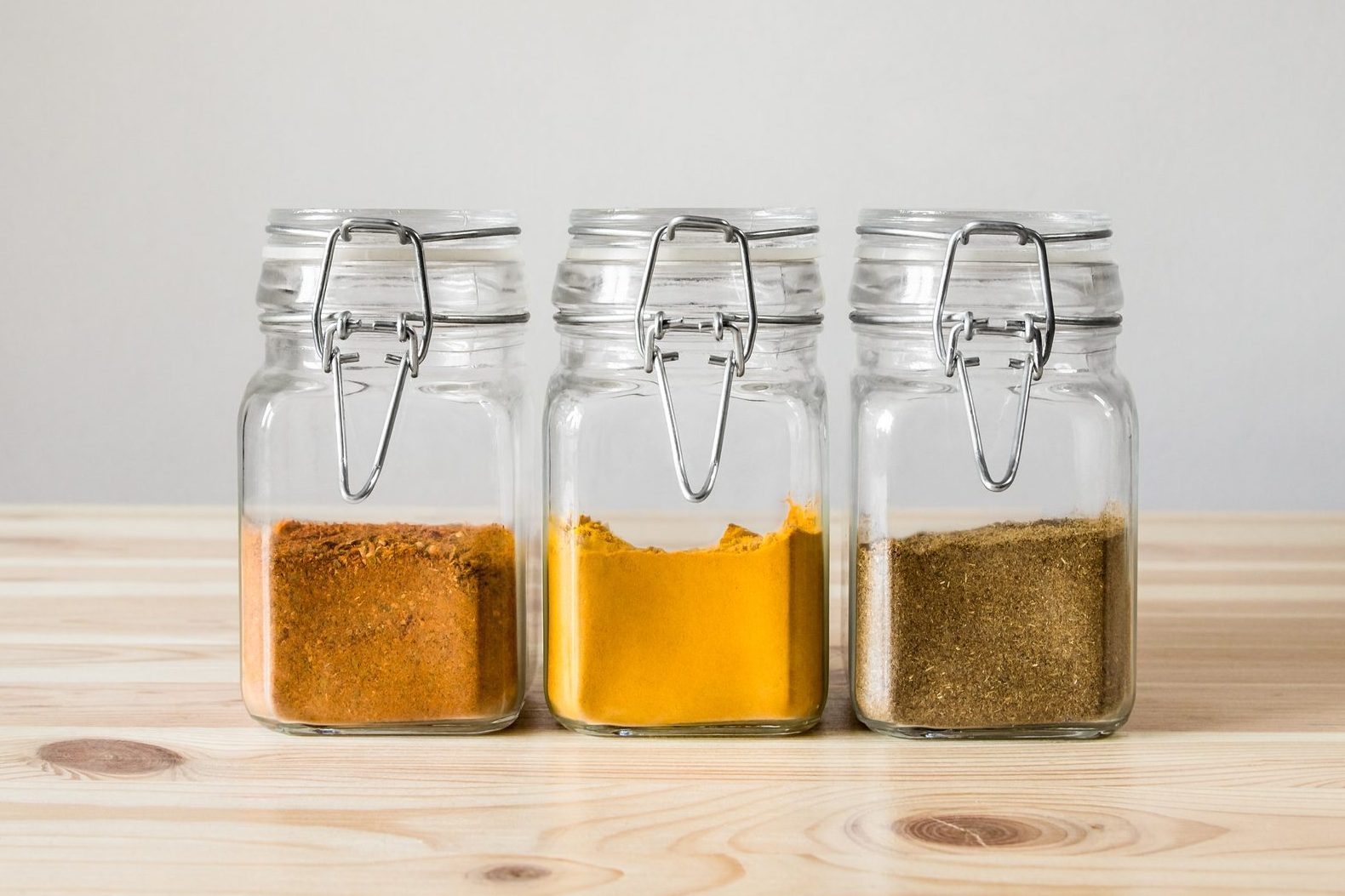 Jars with spices on light wood table.