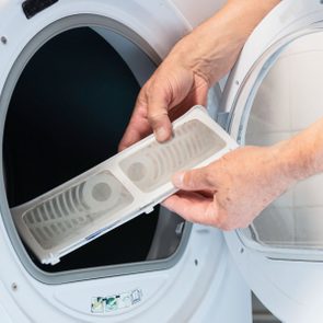 A person cleaning the lint of a dryer
