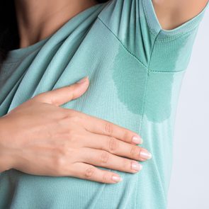 woman lifting her arm to reveal sweat stains in shirt