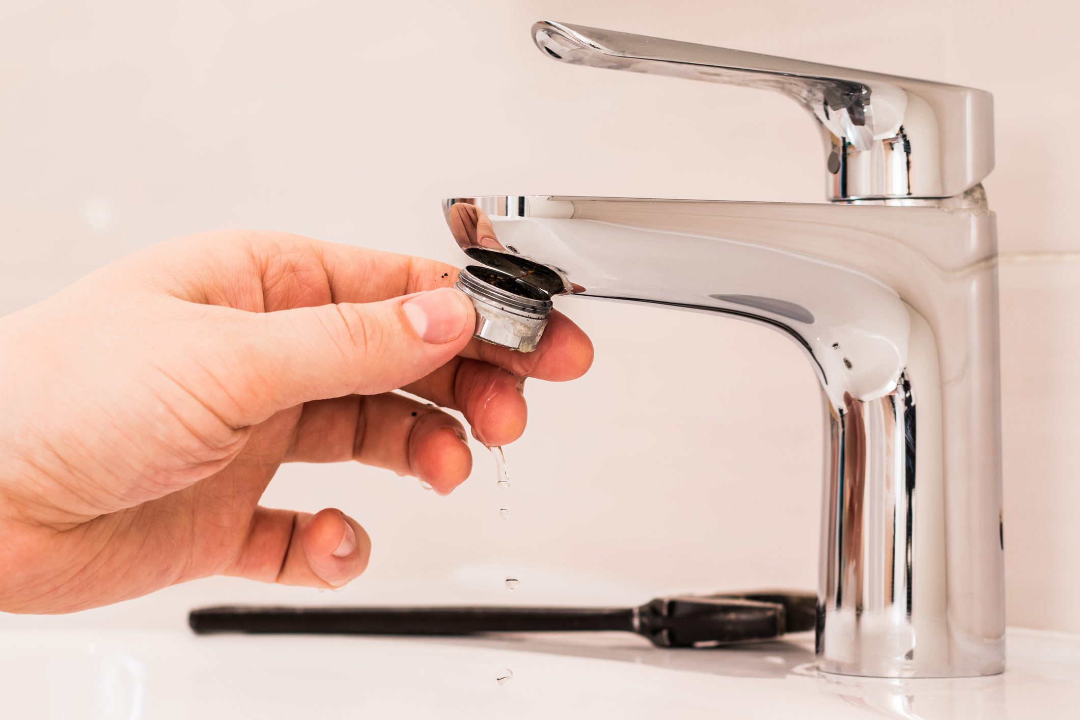 Sediment in tap water. Faucet cleaning. The person unscrews the aerator.