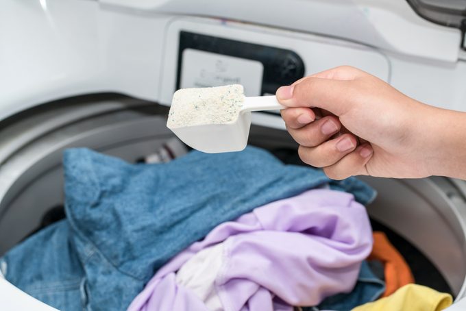 Hand pouring detergent into the washing machine