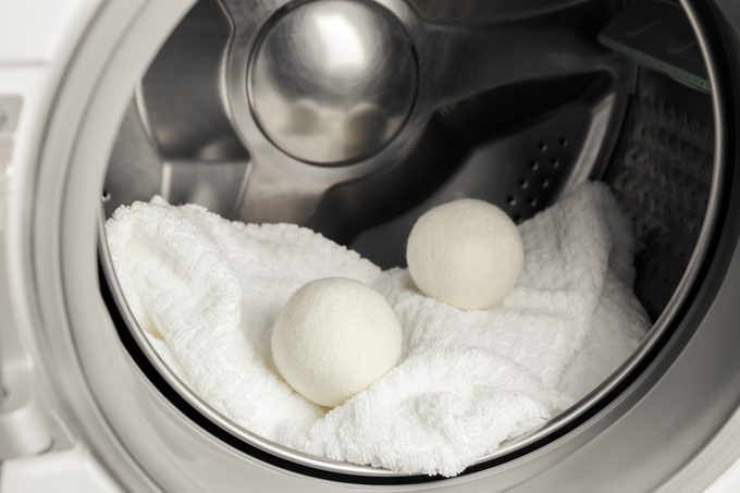 Using wool dryer balls for more soft clothes while tumble drying in washing machine concept. Discharge static electricity and shorten drying time, save energy.