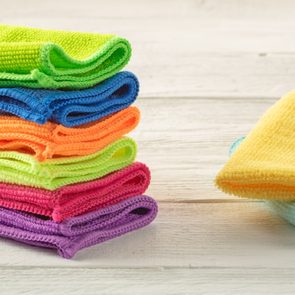 Stack of kitchen microfiber towels in bright colors on a white wooden background