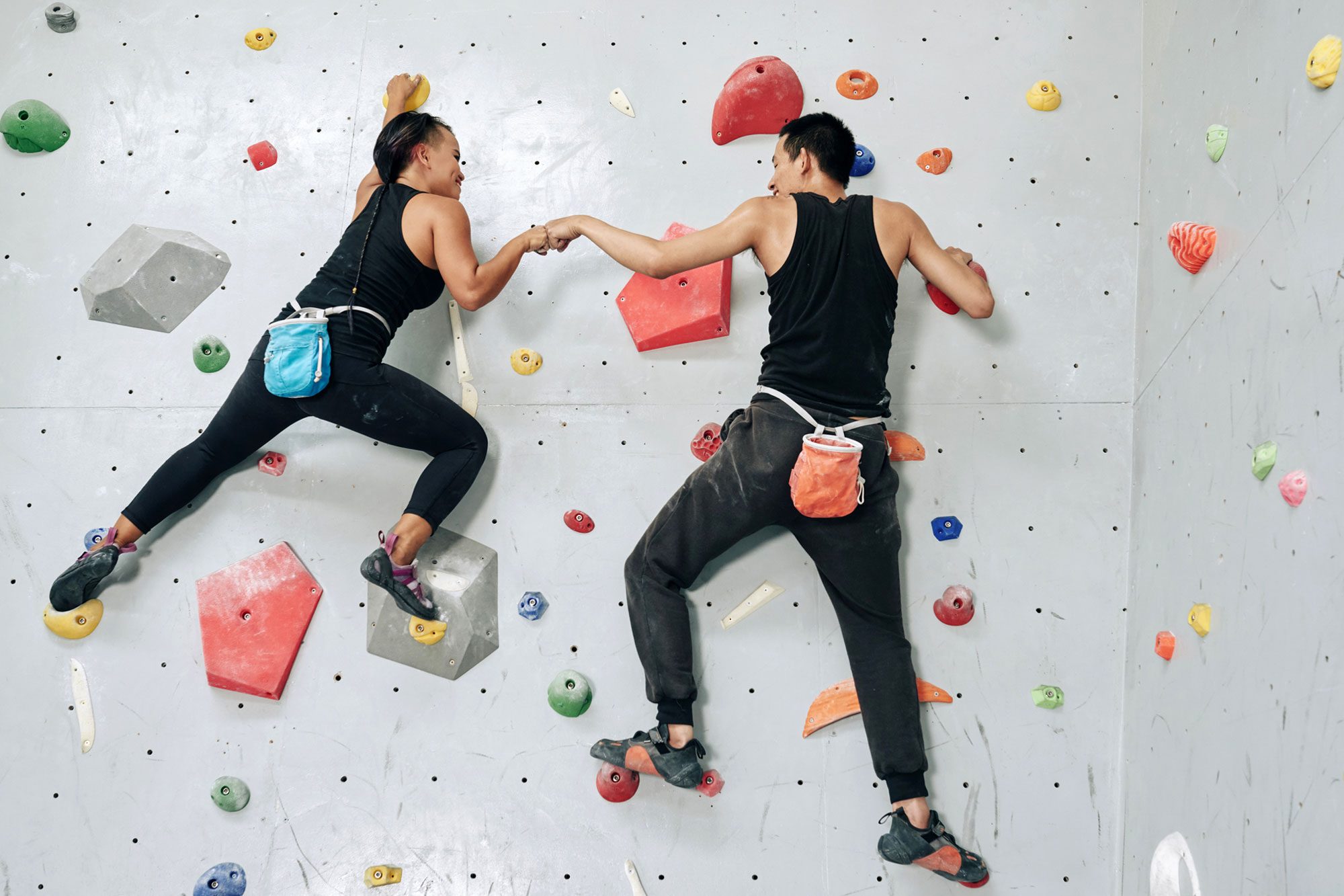 Supportive Sportspeople Climbing Wall Up