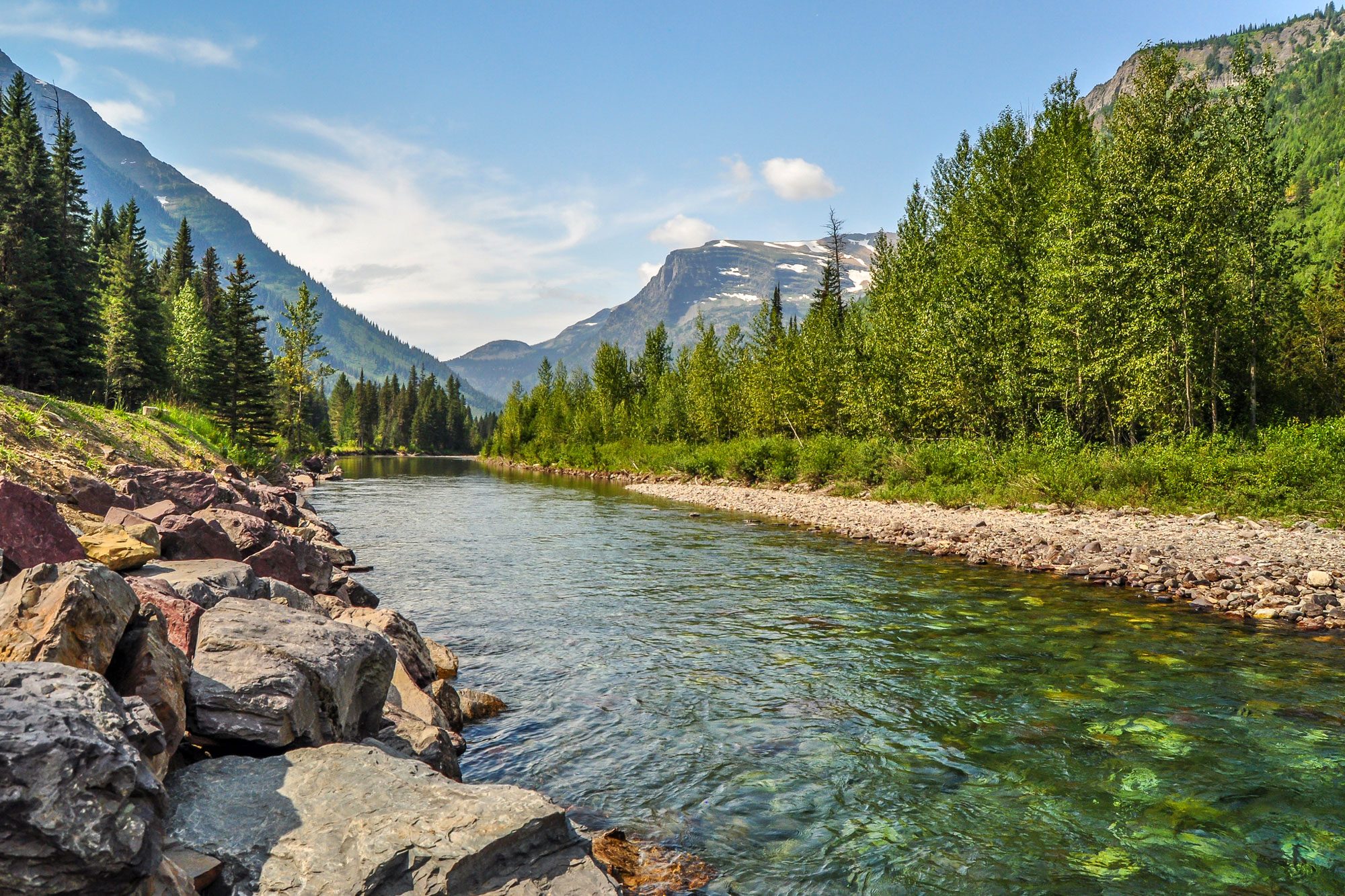 A River Runs Calmly Through A Valley In Glacier National Park Of Montana