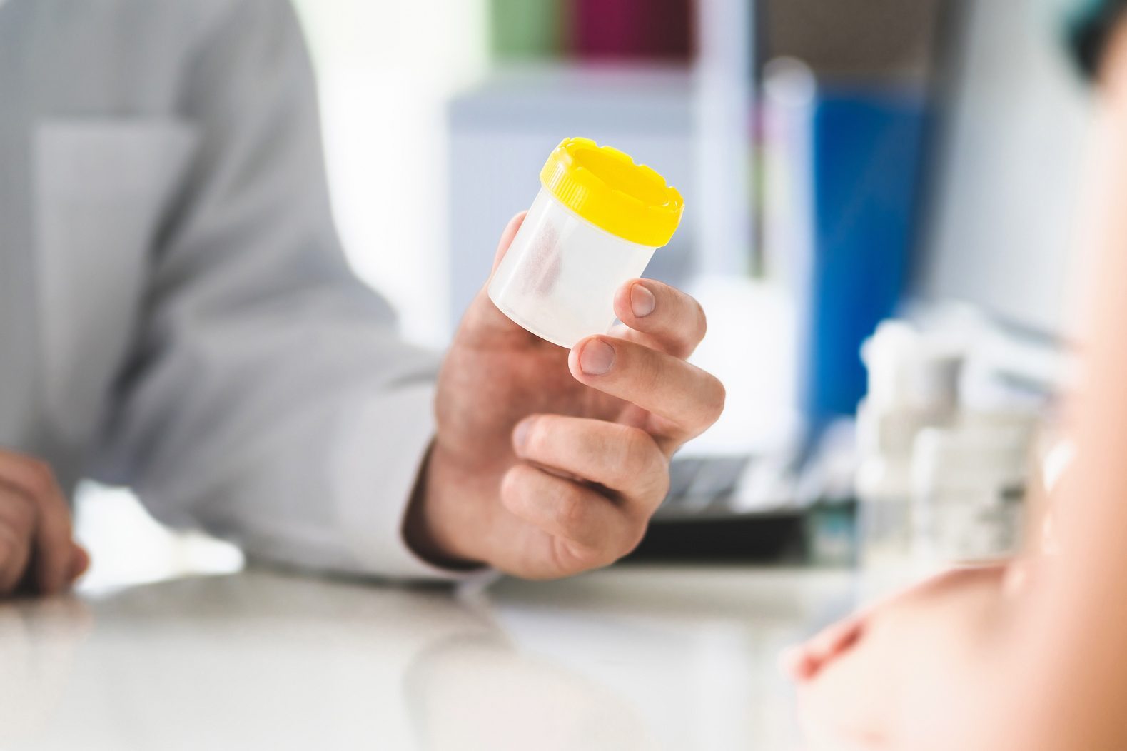 Doctor, patient and urine test cup. Physician giving pee container to a woman in clinic or hospital emergency room. Urinary sample for medical exam in hospital.