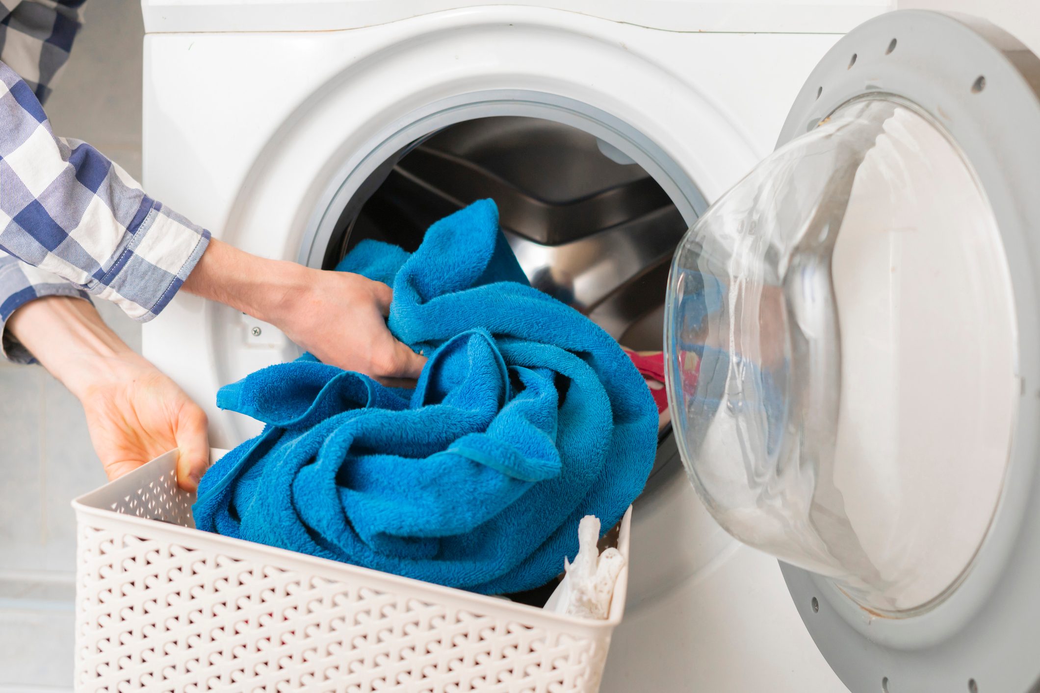 persons hand put dirty clothes in the washing machine b