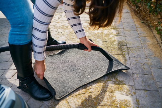 Closeup shot of a young female driver cleaning carpets with a vacuum cleaner