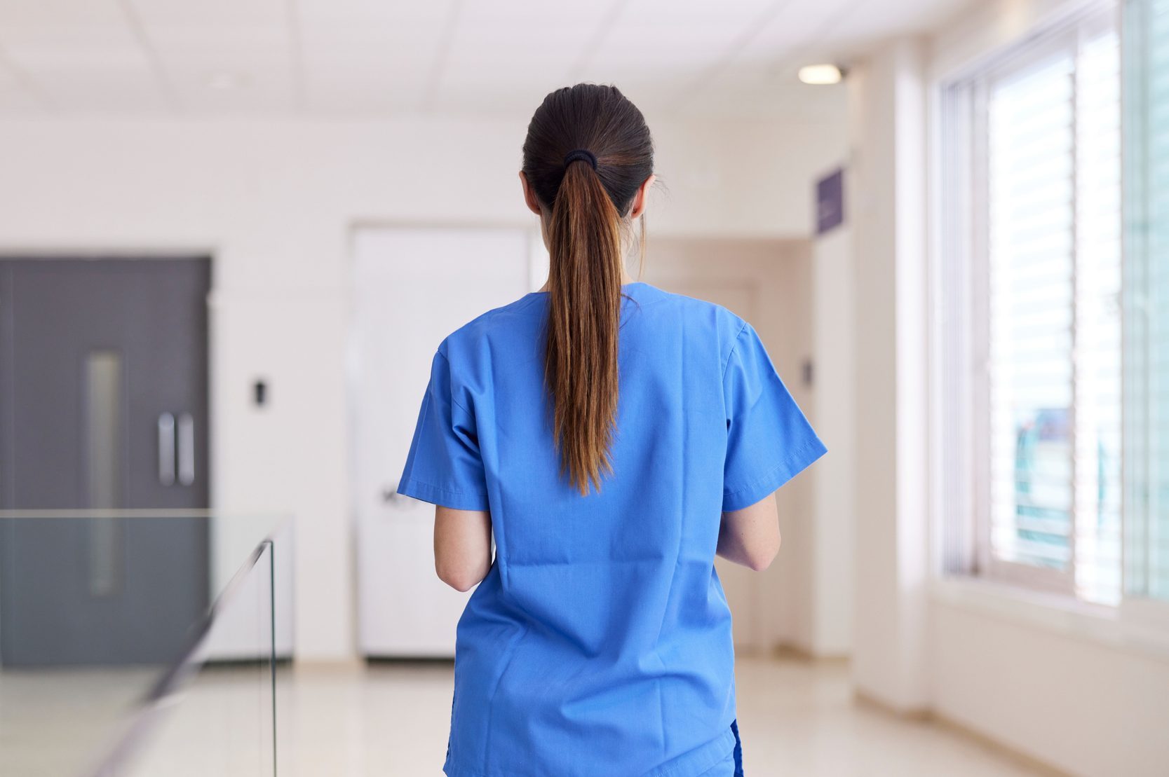 A nurse walks down the corridor in a hospital.