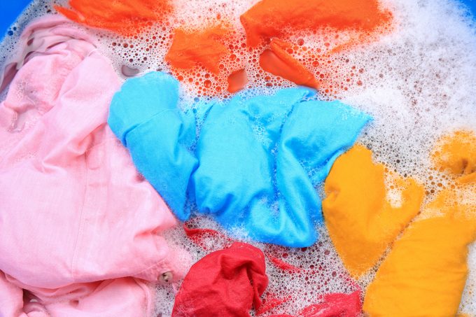 Colorful clothes in suds, top view. Hand washing laundry
