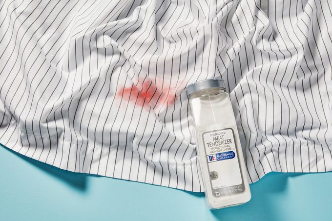 Blood stain on sheets with meat tenderizer package nearby, on blue background