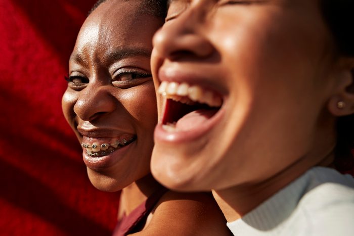 smiling multi-ethnic friends against red wall