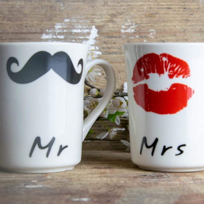 Two coffee cup with face of man and woman together with heart on wooden table. Concept of happy Valentines day
