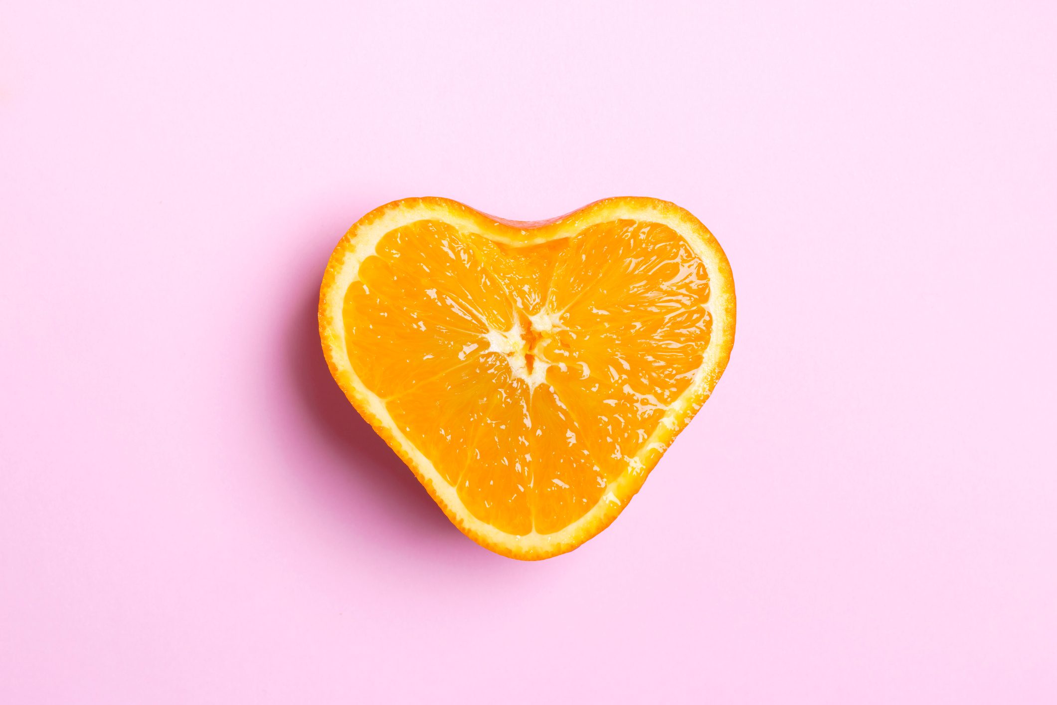 Heart Shaped Orange Half On Pink Background