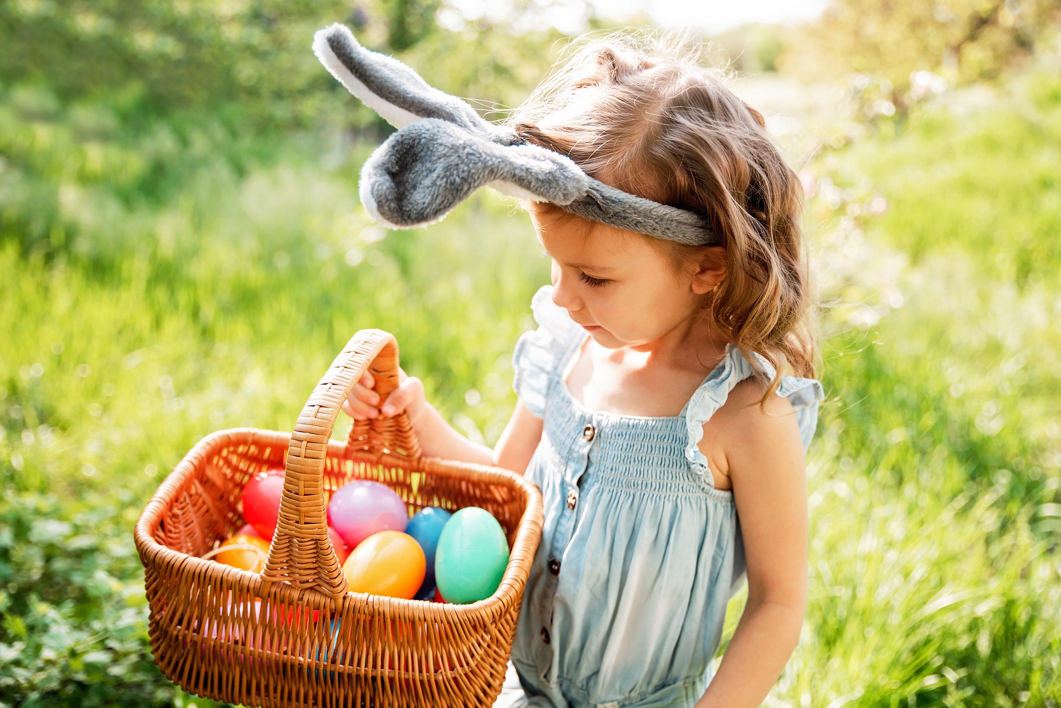 Baby with basket full of colorful eggs. Easter egg hunt.