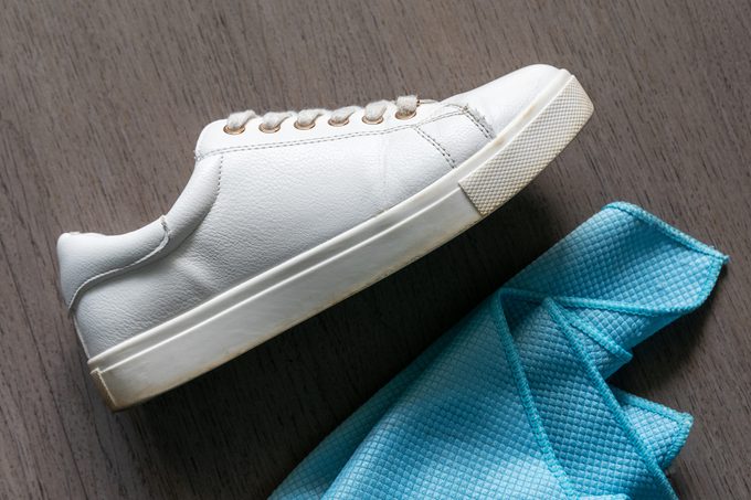 A white sneaker next to a cleaning cloth
