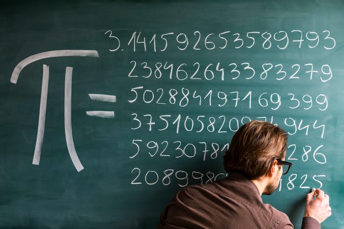 Teacher, student, scientist hand writing Pi numbers on green chalkboard