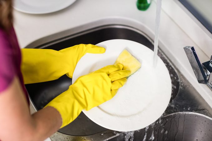 Woman washing plate at kitchen washbasin