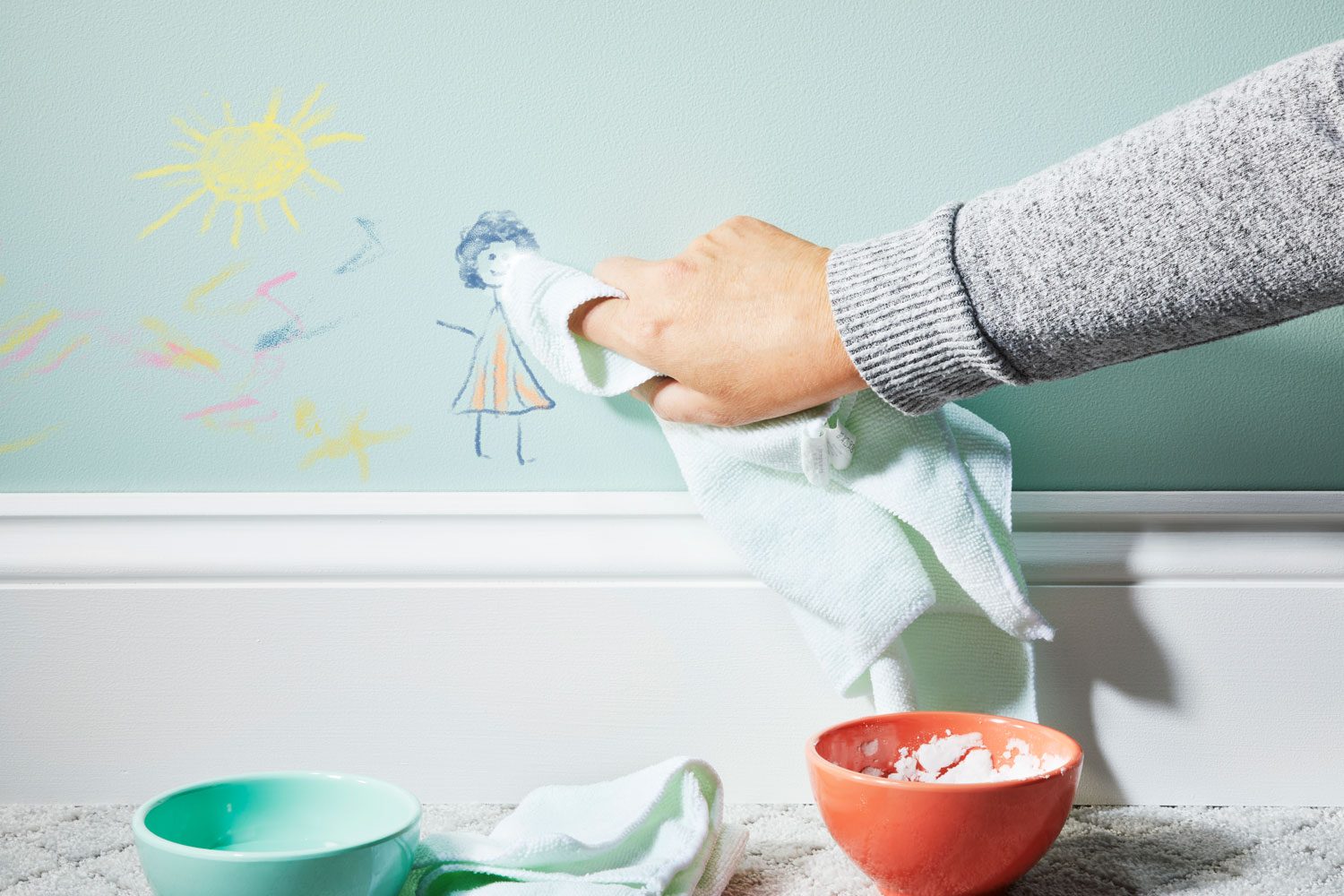 applying paste to the crayon markings on the wall