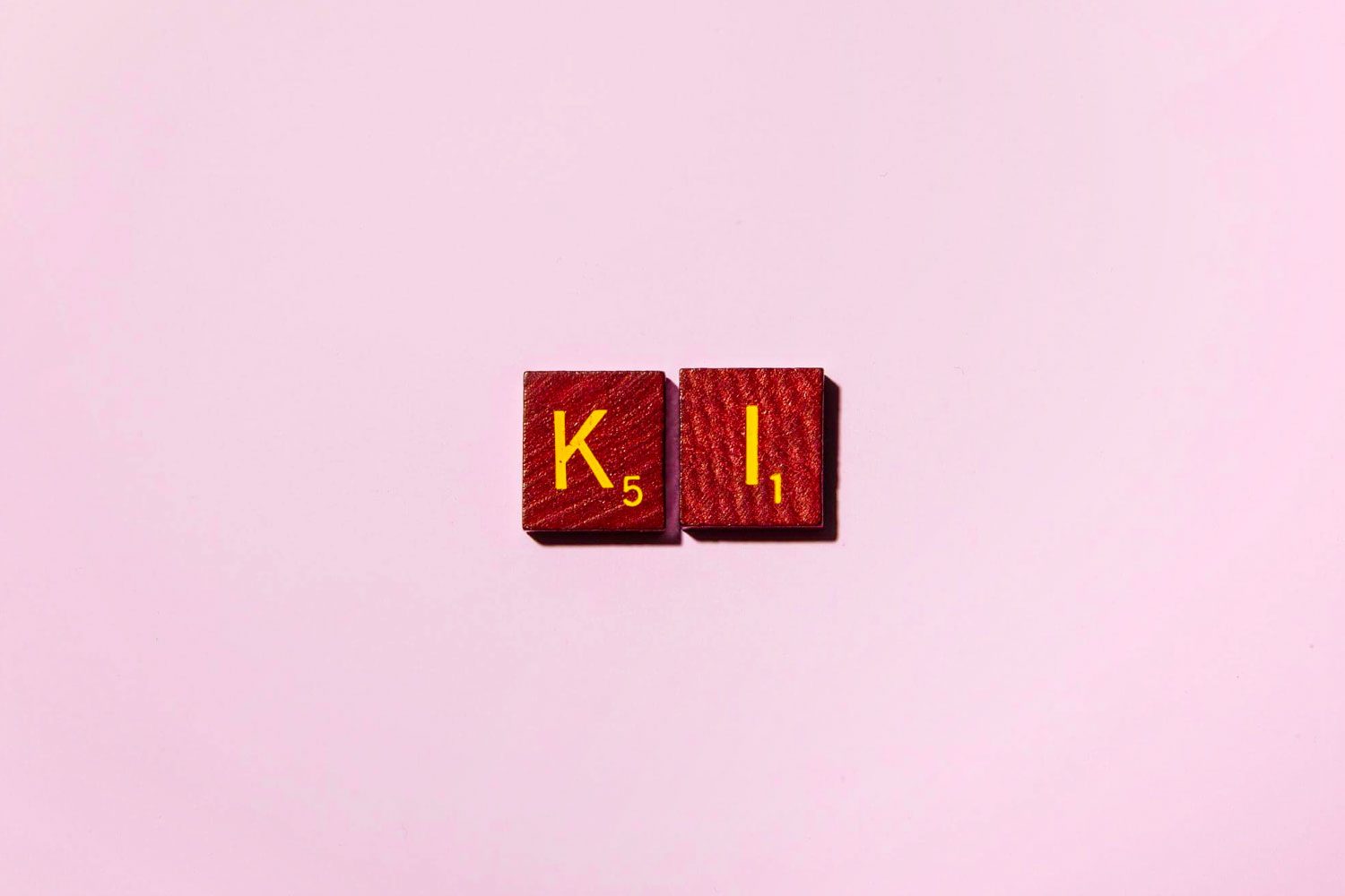 "KI" in scrabble letters on a pink background