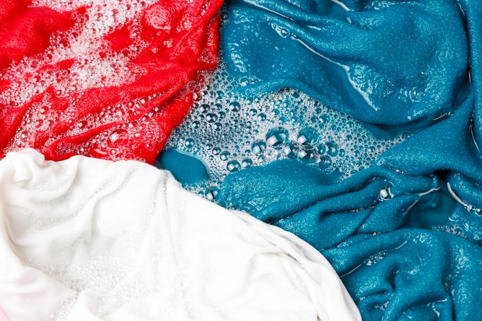Colorful clothes washed with a basin with soap bubbles, close-up, top view