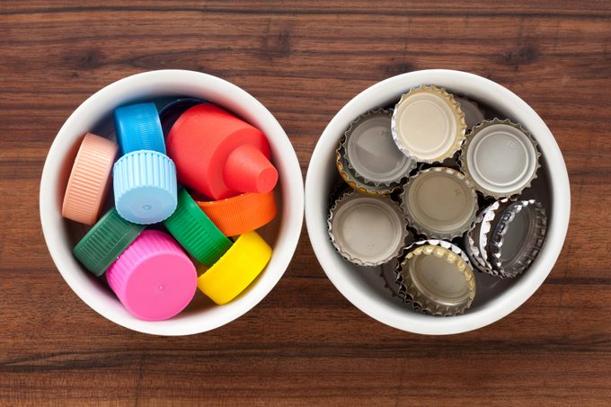 Top view of two bowls side by side, one with plastic bottle caps and one with metal bottle caps