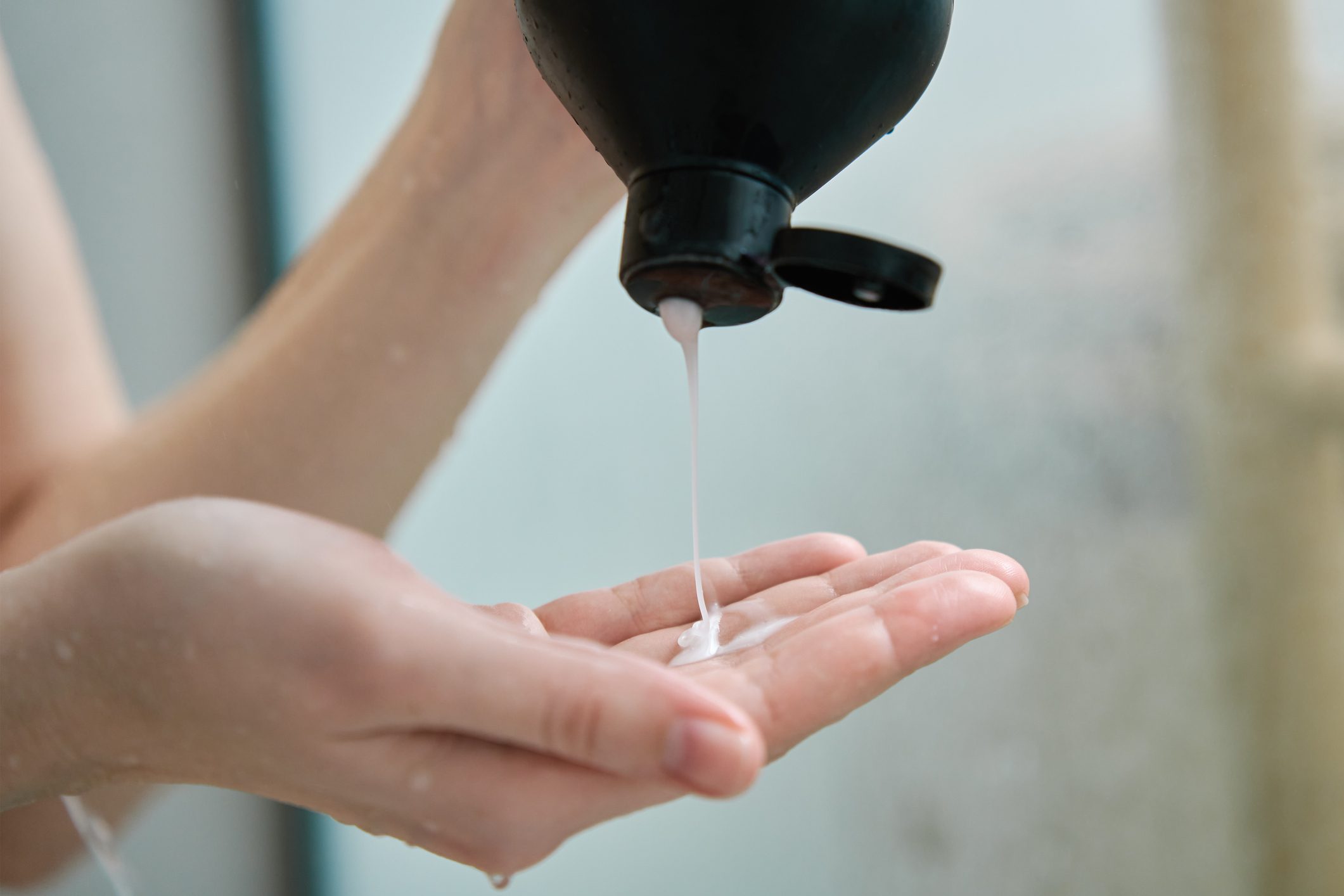 Woman pouring shampoo on hand in bathroom
