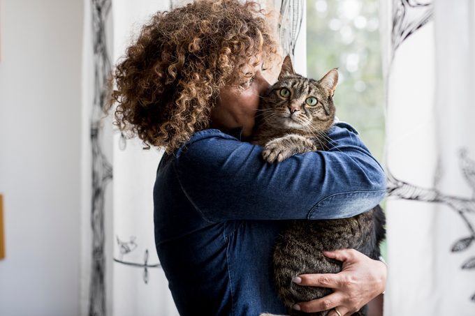 Woman cuddling with cat by the window