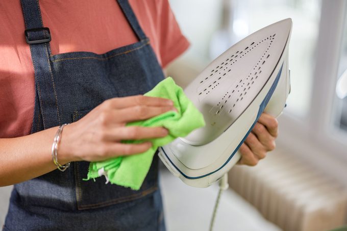 Woman Cleaning Iron With A Microfiber Cloth