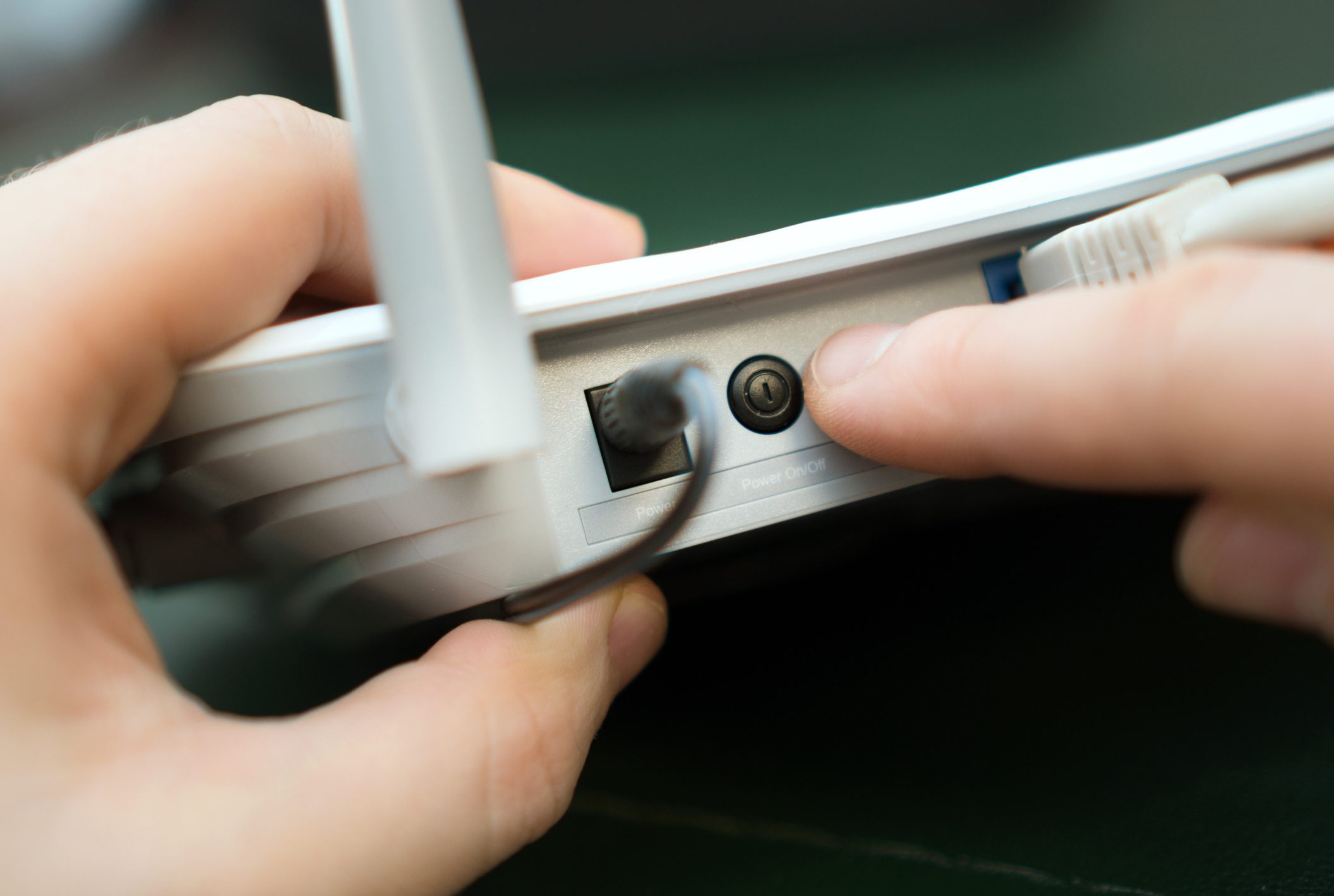 Man pressing power button on the wifi router.