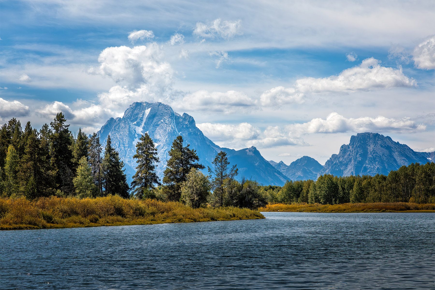 The Grand Teton mountain range behind a lake on a cloudy day