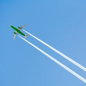 Green Airplane With White Trails On A Blue Sky