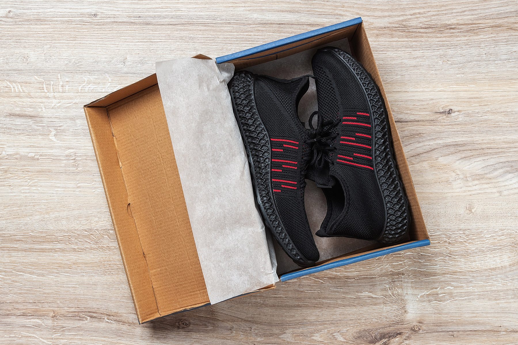 Pair of black mesh sneakers in a brown cardboard box on the floor