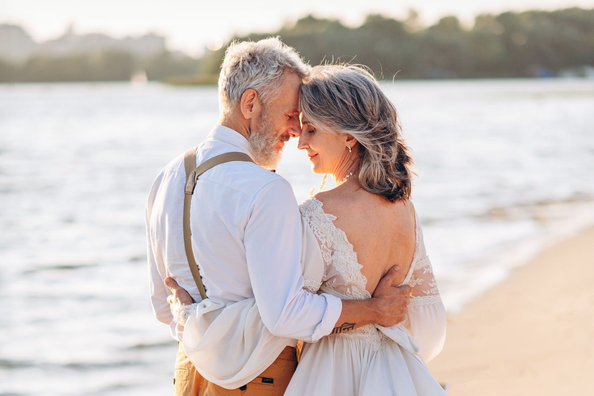 Stylish Couple Of Elderly Newlyweds Stand Embracing On River Bank