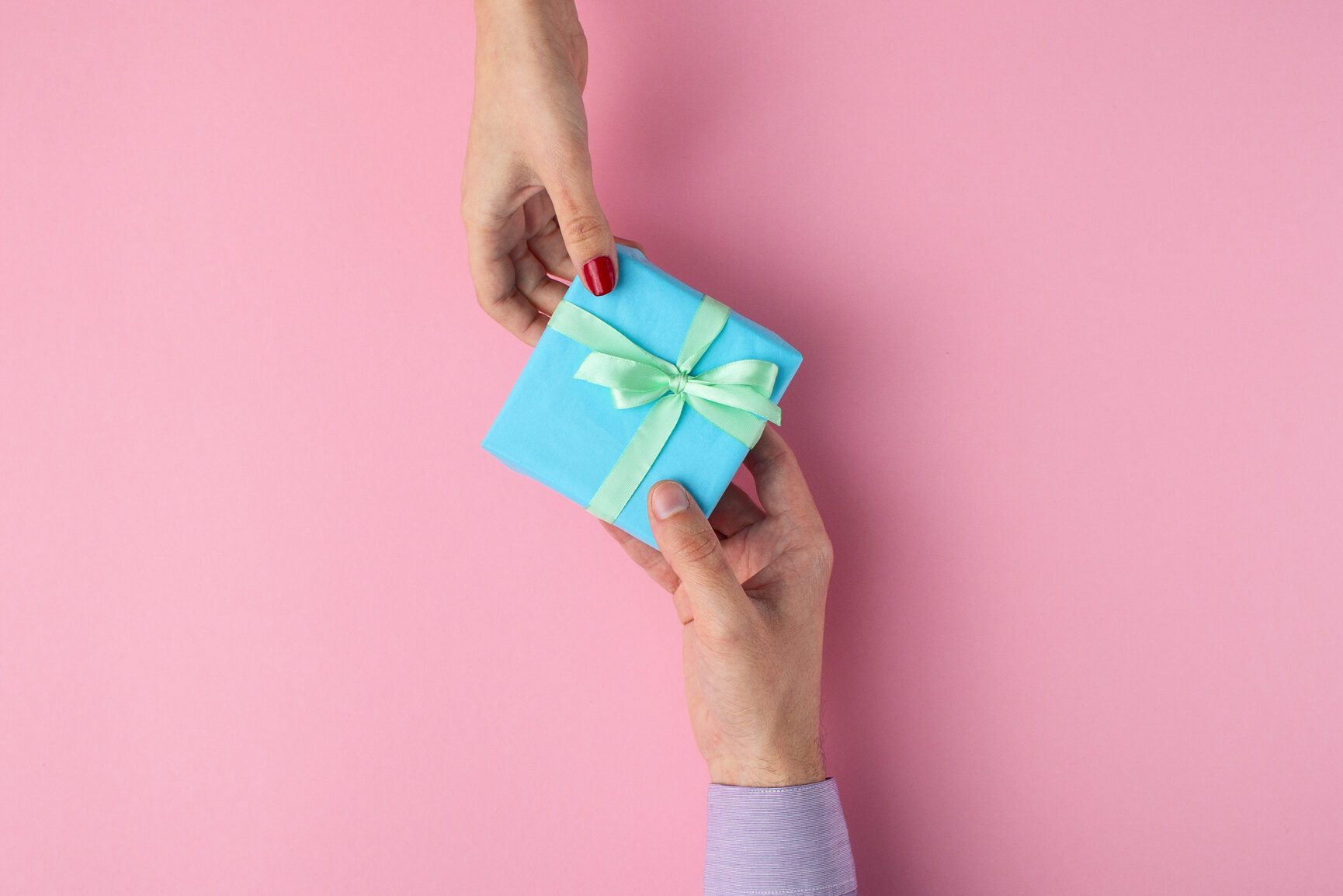 man gives a girl a gift from hand to hand,box wrapped in decorative paper on background, the concept of holidays, love and care, top view