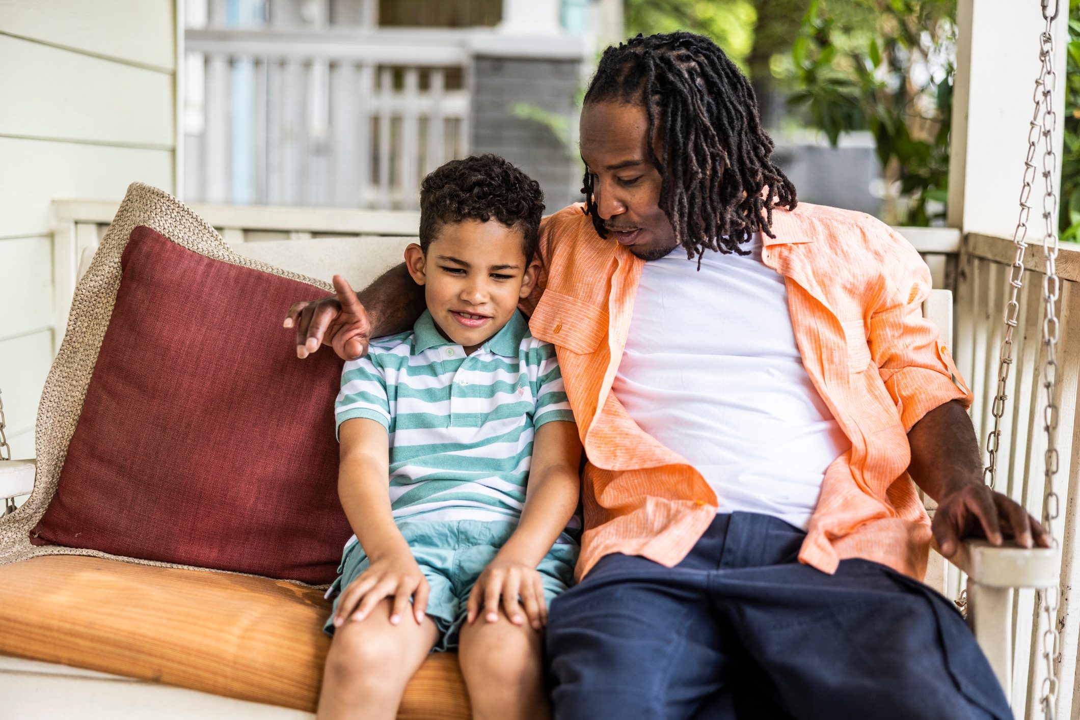 Father and son sitting on front porch swing together