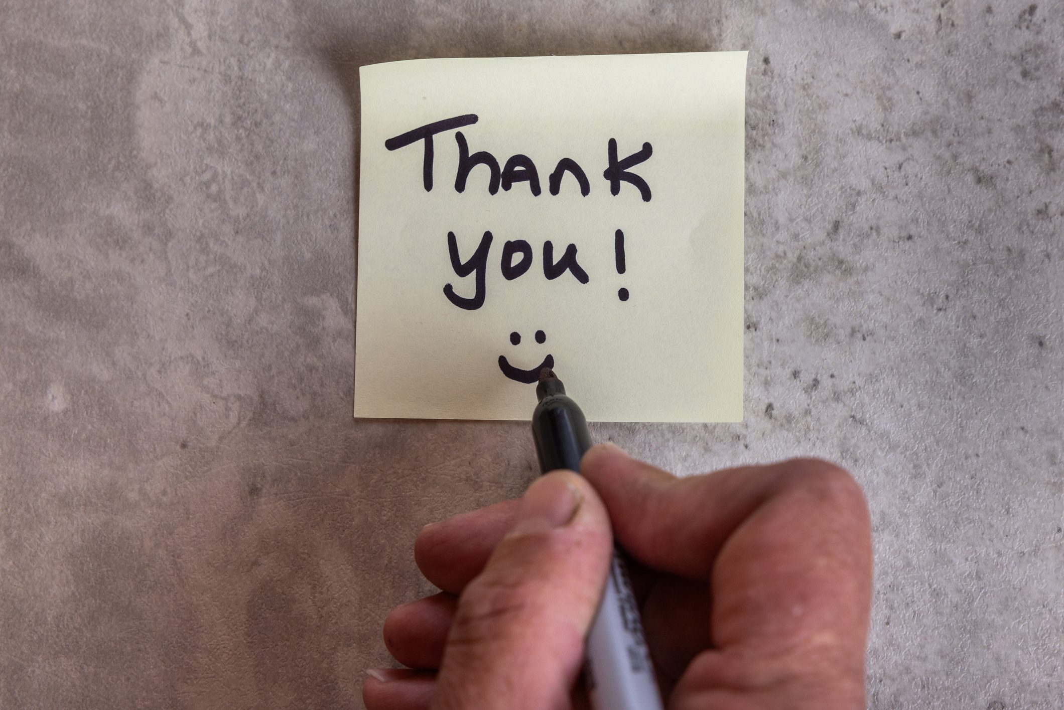 A person is writing a thank you note on a piece of paper