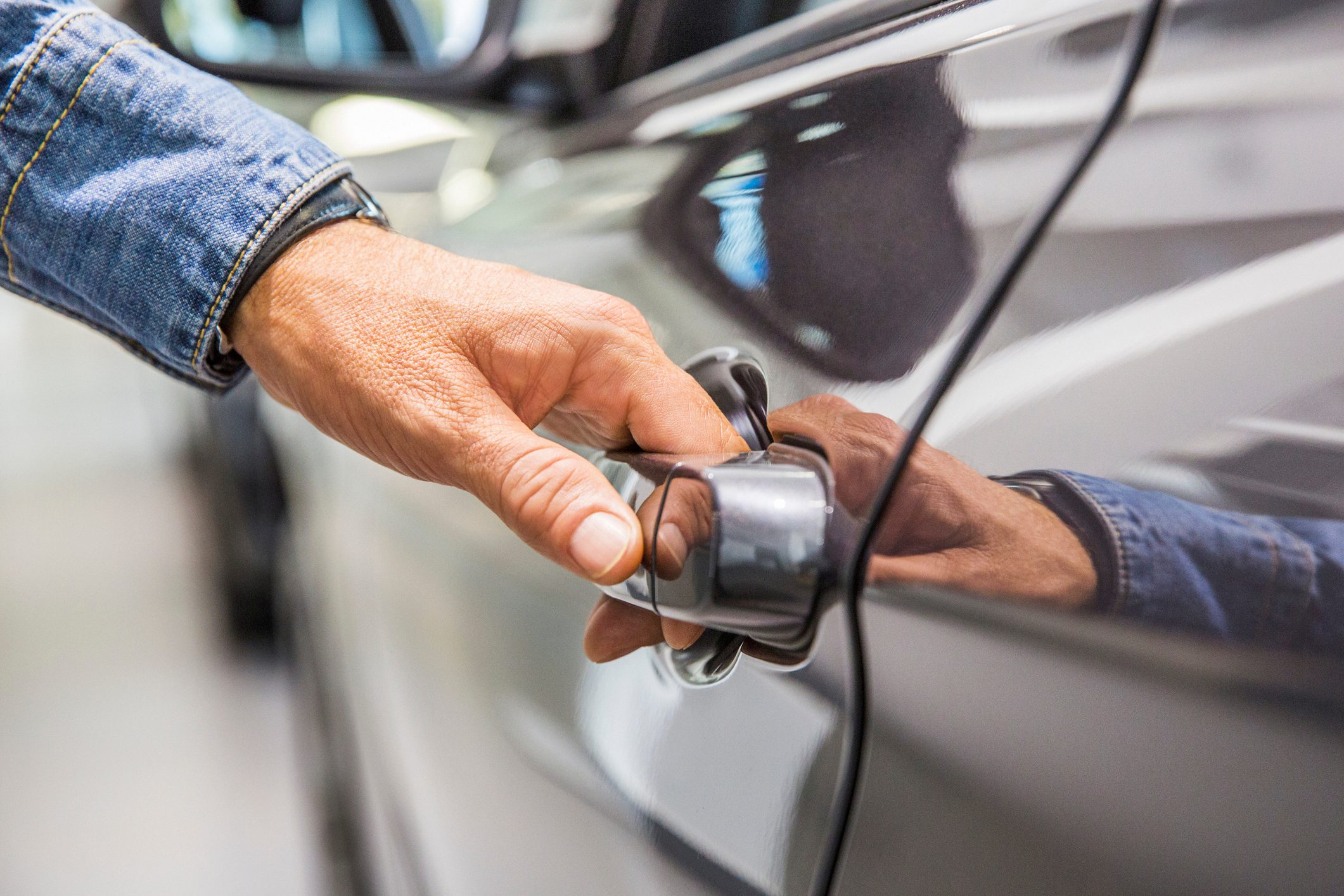 Man's hand on grey car door handle