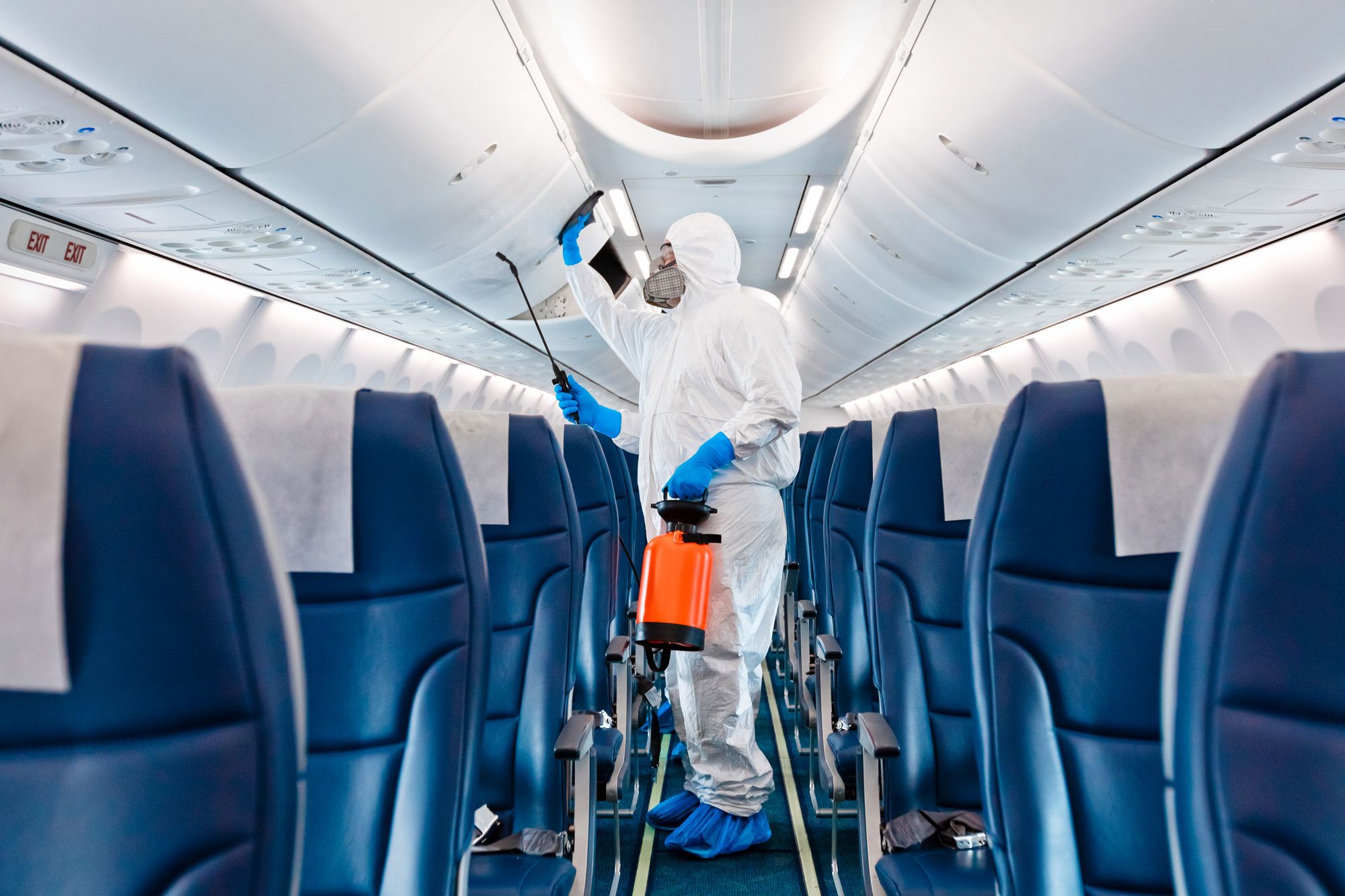 Men In Protective Suits And Masks Disinfecting Airplane