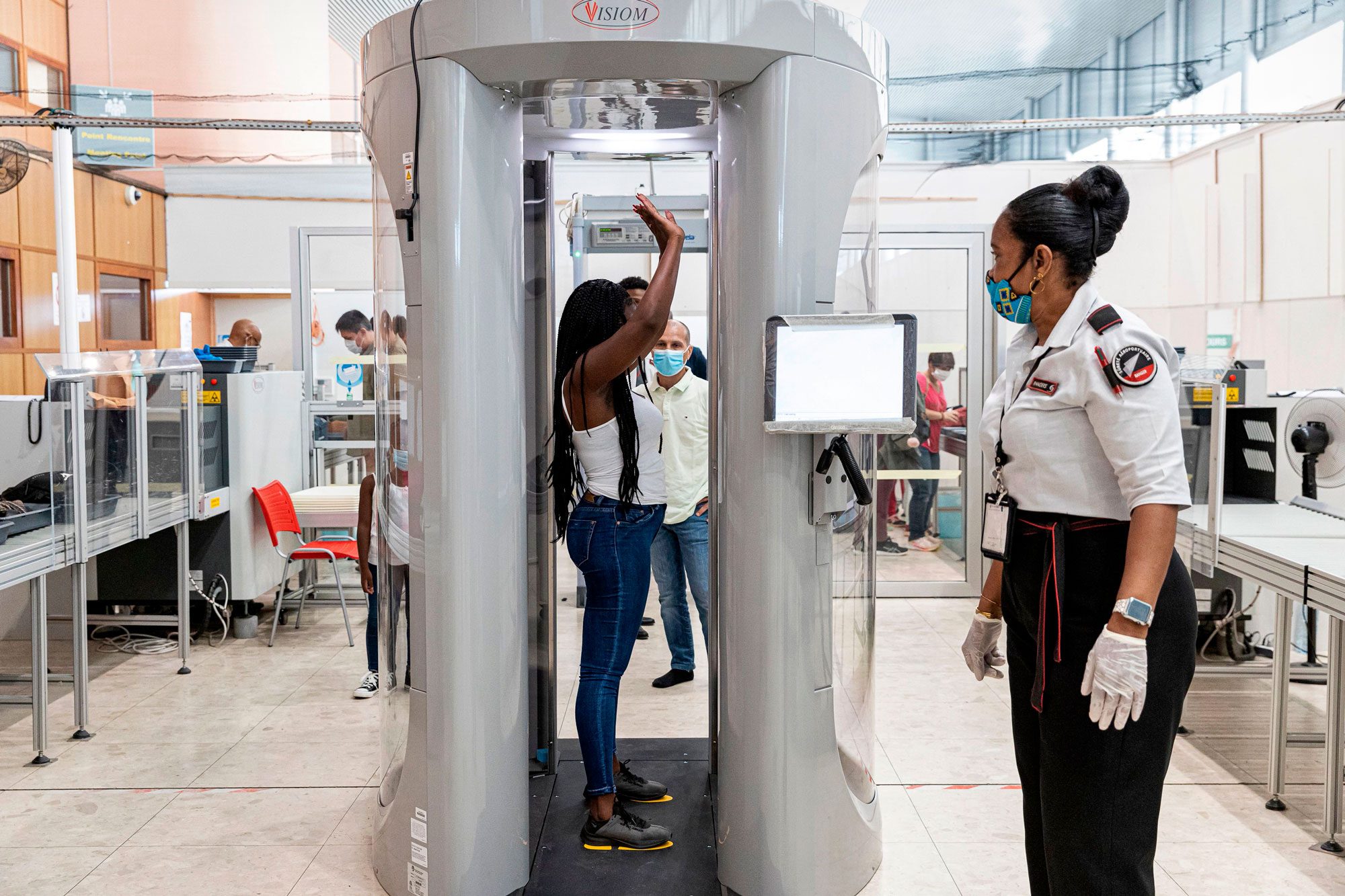 An Airport Security Officer Waits As A Passenger Passes Through A Millimeter Wave Scanner Airport Body Scanner