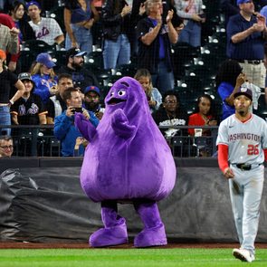 McDonald's character Grimace is seen on the field behind Nasim Nunez #26 of the Washington Nationals during the seventh inning against the New York Mets at Citi Field on September 16, 2024 in New York City.