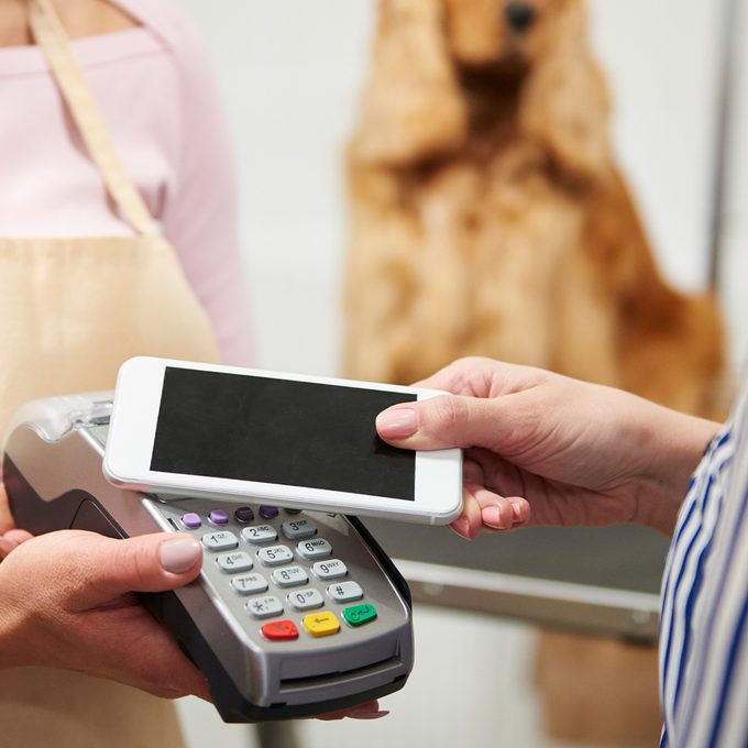 How Much To Tip In Every Situation woman paying the dog groomer via smartphone