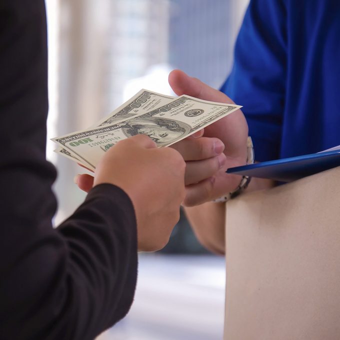 How Much To Tip In Every Situation man paying the mail man via cash