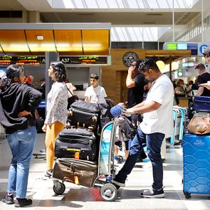 Travelers wait with their luggage in the international terminal at Los Angeles International Airport (LAX).