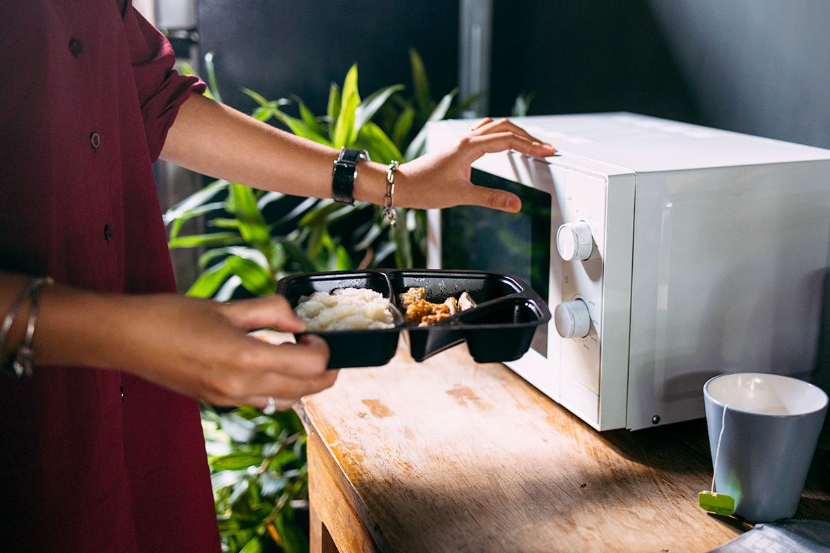 A person heating food in the microwave.