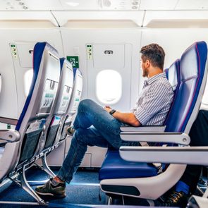 Male Passenger In Smart Casual Clothing Flying In The Exit Row On An Airplane